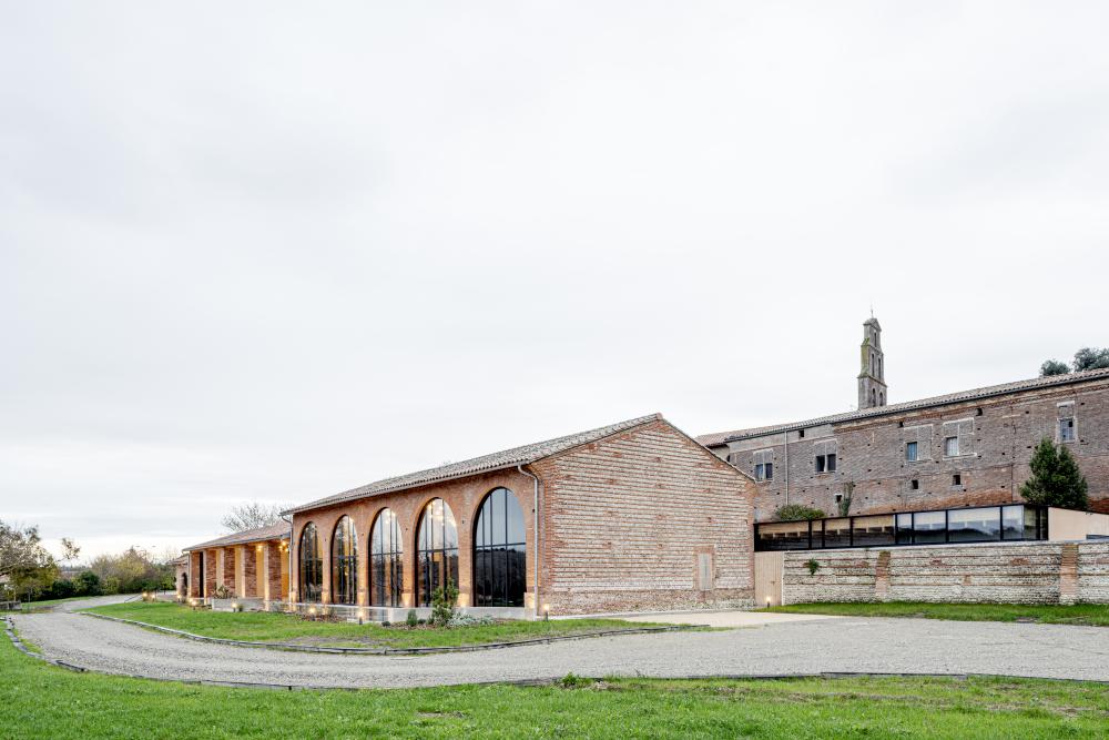 Vue du corps de bâtiment rénové et de l’extension émergeant au-dessus du mur d’enceinte - Copyright : Antoine Huot, OECO Architectes